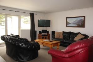 a living room with black leather furniture and a television at Marine Haven - Napier Holiday Home in Napier