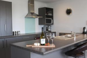 a kitchen with a bottle of wine and glasses on a counter at Marine Haven - Napier Holiday Home in Napier