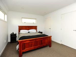 a bedroom with a wooden bed with two pillows at Marine Haven - Napier Holiday Home in Napier