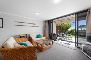 a living room with a couch and a tv and a table at The Sandcastle - Papamoa Holiday Apartment in Papamoa