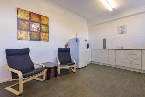 una sala de espera con 2 sillas y nevera en Getaway Villas Unit 385, en Exmouth