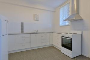 cocina con armarios blancos y fogones en Getaway Villas Unit 385, en Exmouth