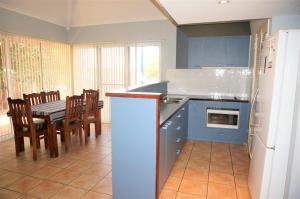 a kitchen with blue cabinets and a table and chairs at Osprey Holiday Village Unit 115 in Exmouth