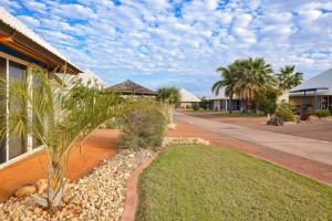a house with a palm tree next to a street at Osprey Holiday Village Unit 123 in Exmouth
