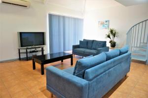 a living room with two blue couches and a television at Osprey Holiday Village Unit 118 in Exmouth