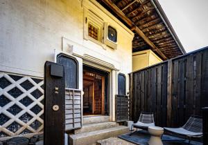 een huis met een deur en twee stoelen op een veranda bij BYAKU Narai in Shiojiri