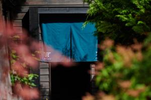 une porte ouverte d'un bâtiment avec un rideau bleu dans l'établissement BYAKU Narai, à Shiojiri