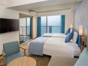 a bedroom with a large bed and a balcony at Atagawa Ocean Resort in Higashiizu