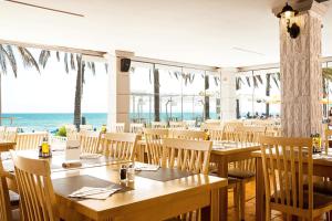 a restaurant with tables and chairs and the ocean at Alexandra Beach Hotel in Nea Kydonia