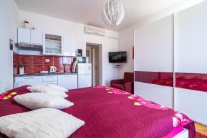 a bedroom with a red bed with pillows on it at Apartments Mara & Petrunjela in Cavtat