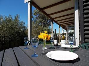 a wooden table with wine glasses and a plate on it at Great Escape - Whangamata Holiday Home in Whangamata