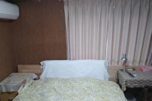 a bedroom with a bed and a lamp and a window at 古民家リゾートハウス　ひみつきち in Kakegawa