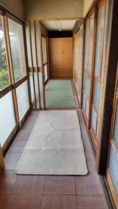 an empty hallway with windows and mats on the floor at 古民家リゾートハウス　ひみつきち in Kakegawa