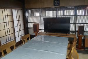um quarto com uma mesa e uma televisão de ecrã grande em 古民家リゾートハウス　ひみつきち em Kakegawa