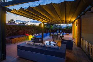 a patio with a couch and an umbrella at ZENLUXE Villa Planet Costa Dorada in Reus