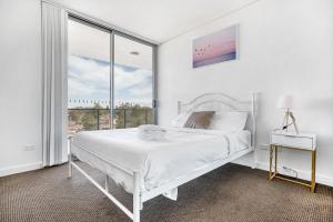 シドニーにあるKOZYGURU Parramatta Lovely 2 BED APT Free Parking NPA006の白いベッドルーム(ベッド1台、窓付)