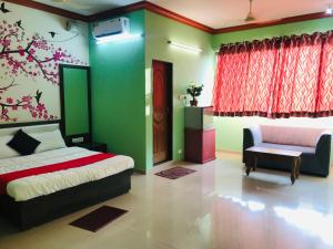 a bedroom with green and red walls and a bed and a chair at STAYMAKER Prakash International in Gonikoppal