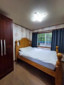 a bedroom with a wooden bed and a window at Mayfare Narsha Pyeongchang in Pyeongchang