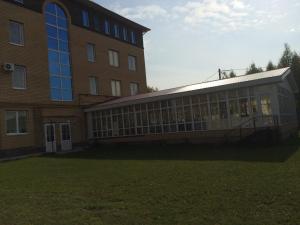 イヴァノヴォにあるMini-hotel Sputnikの煉瓦造りの大きな建物で、草原の横に窓があります。
