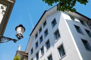 - un bâtiment blanc avec un éclairage de rue à côté dans l'établissement Boutique Hotel Helmhaus Zürich, à Zurich