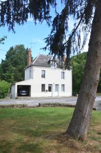 Una casa blanca con un árbol delante. en studio "Au Bord de l'Eau" 2, en Chambon-sur-Voueize