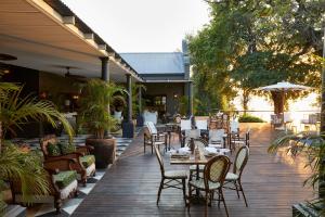 un patio con mesas y sillas en una terraza de madera en Zambezi Grande Private Game Experience en Mafuta