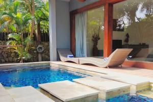 una piscina con 2 sillas junto a una casa en VIILA JAHE, en Kuta Lombok
