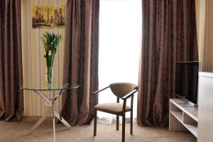 a living room with a glass table and a chair and a television at Hotel Victoria in Kapchagay