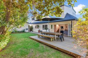 a wooden deck with a table and chairs on it at Sandy Feet - Papamoa Beach Holiday Home in Papamoa