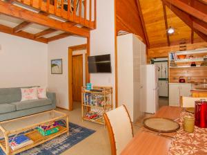 een woonkamer met een bank en een tafel bij Cedar Cottage - Tairua Holiday Home in Tairua