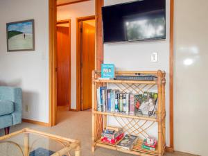 een boekenplank met boeken en een televisie aan de muur bij Cedar Cottage - Tairua Holiday Home in Tairua