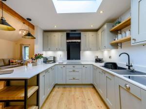 a large kitchen with white cabinets and a skylight at Rinstone Lodge, Thornton-Le-Dale. Moors cottage with hot tub in Thornton Dale +8 photos