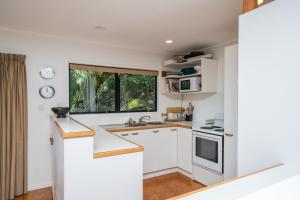 eine Küche mit weißen Schränken und einem Fenster in der Unterkunft Langs Hideaway - Langs Beach Holiday Home in Langs Beach