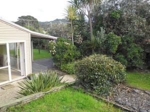 a yard with a house and some bushes and trees at Ocean Beach Honey - Tairua Holiday Home in Tairua