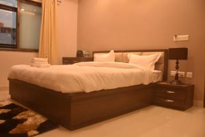 1 dormitorio con 1 cama grande con sábanas y almohadas blancas en Hotel Singh Comfort Inn, en Gorakhpur