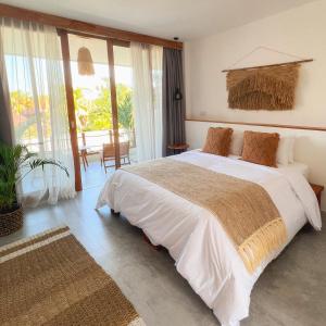 a bedroom with a large bed and a balcony at Arya Wellness - female only in Ubud