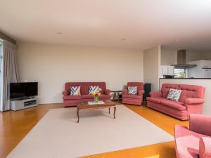 una sala de estar con 2 sofás rosas y una mesa. en Roberts Retreat - Mangawhai Holiday Home, en Mangawhai