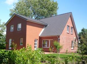 una casa de ladrillo rojo con techo negro en Nordsee-1, en Vollerwiek