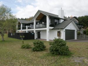 a large white house with a black roof at Lake Magic - Motuoapa Holiday Home in Turangi