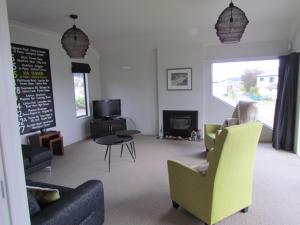 ein Wohnzimmer mit einem Sofa, Stühlen und einem Tisch in der Unterkunft Lake Magic - Motuoapa Holiday Home in Turangi