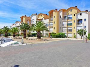 a large building with palm trees in front of it at Gruissan les MARINES II in Gruissan