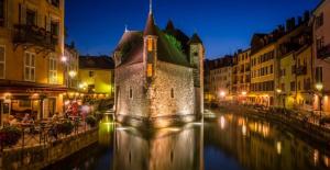 a building on a river in a city at night at Appartement Standing Cœur d'Annecy in Annecy