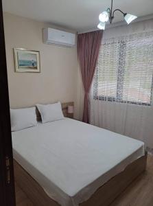 a bedroom with a large white bed in front of a window at Апартамент Амира 3 in Balchik