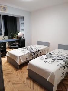 a bedroom with two beds and a desk and a chair at Апартамент в най-хубавия квартал на Варна in Varna City