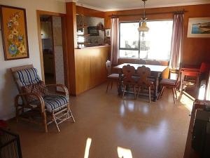 a living room with a dining room table and chairs at Cute Cottage - Cooks Beach Bach in Cooks Beach
