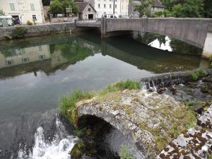 un puente sobre un río con una cascada en GITE LA PETITE ECLUSE EN BORD DE LOUE, en Lods