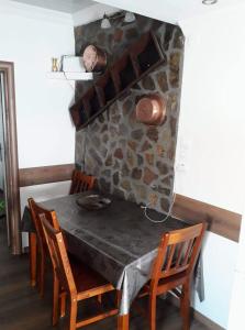 a dining room table with chairs and a stone wall at Vasilis traditional House in Samothráki
