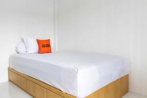 a bed with white sheets and orange pillows on it at KoolKost near Hang Nadim Batam Airport (Minimum Stay. 30 Night) in Nongsa