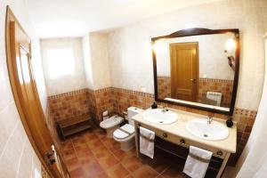 a bathroom with two sinks and a toilet and a mirror at Casa con Encanto,disfruta de su paz y tranquilidad in Adzaneta