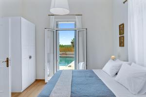 a white bedroom with a bed and a large window at Villa Remedio in Néon Khoríon